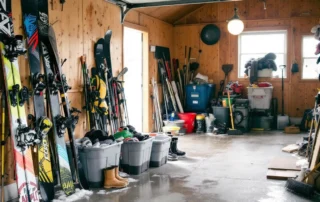 Winter sports equipment and seasonal gear accumulated along garage walls after Central Oregon winter