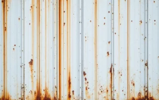 Rust staining and moisture damage on white garage door panel from riverside humidity exposure