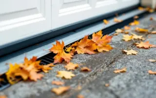 Autumn leaves clogged in garage door track and floor drain creating maintenance obstruction